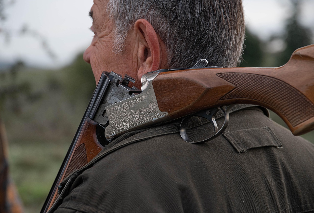 Close-up of a shotgun carried over the shoulder in a rural setting, representing farm security